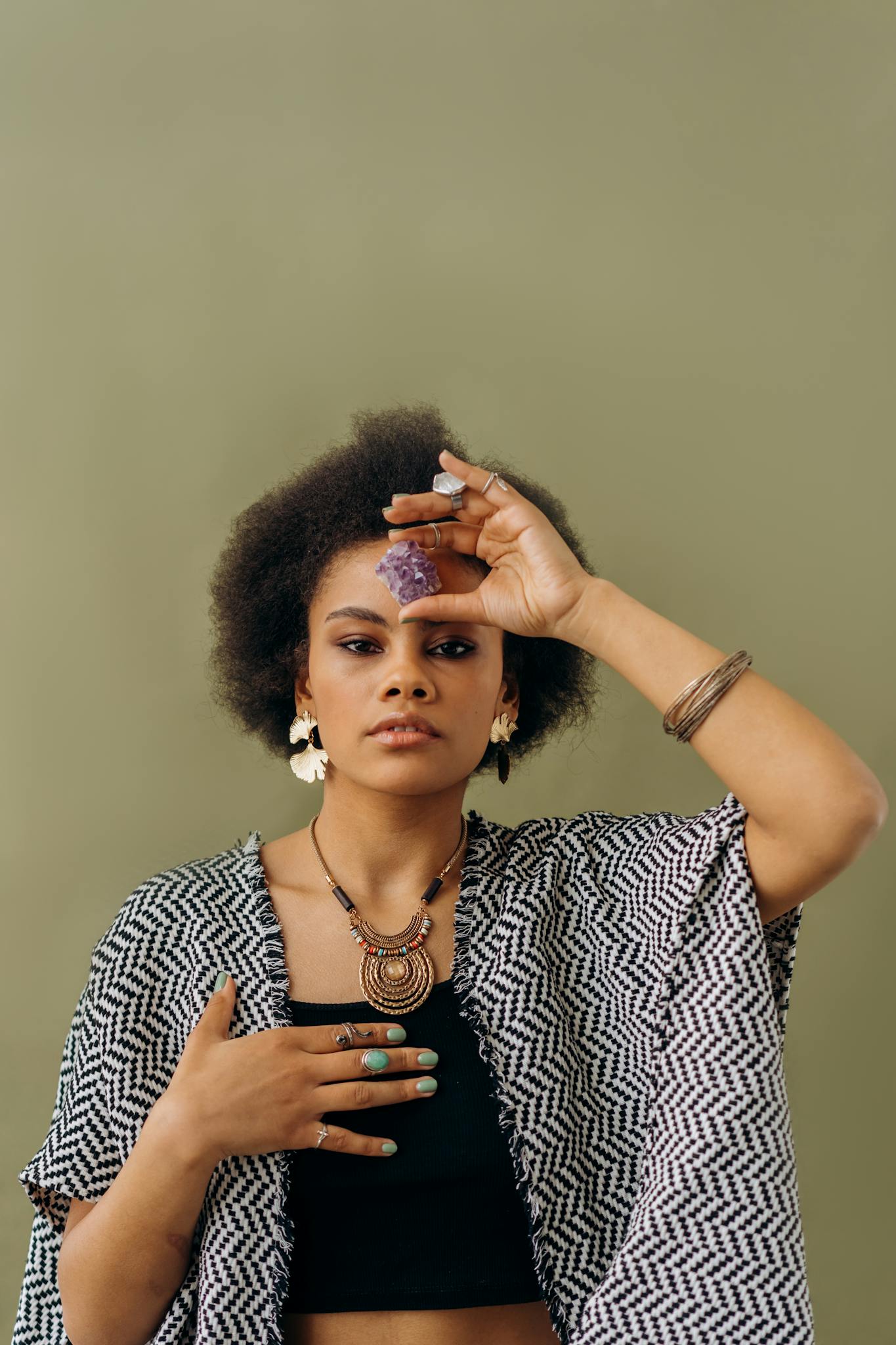 A young woman holds an amethyst crystal, embodying spiritual balance and meditation indoors.