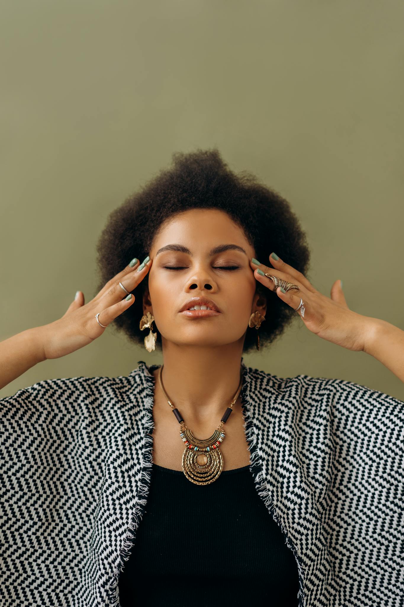 Young woman practicing meditation with eyes closed, adorned with elegant jewelry. Calm and serene aura.
